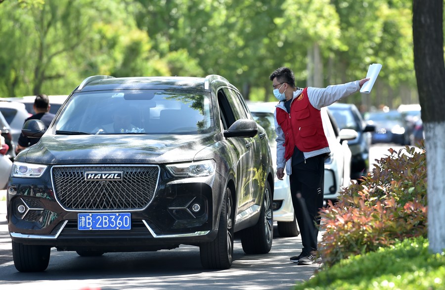 Seorang sukarelawan menunjuk arah kepada pelancong yang berkereta di Zibo, provinsi Shandong, timur China pada 29 April 2023. (Foto oleh Huangpu Xiaowen/Xinhua)