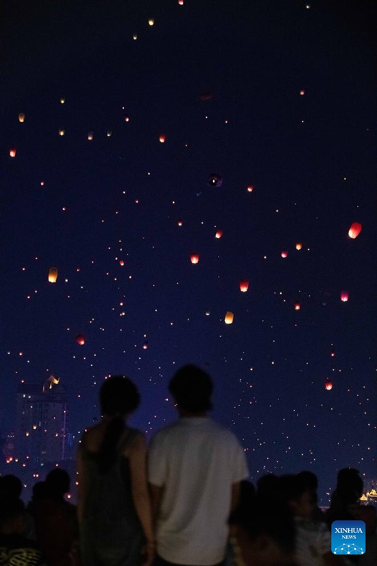 Orang ramai menyaksikan lantera Kongming, belon kertas udara panas kecil yang berterbangan di udara di Jambatan Xishuangbanna, Bandar Jinhong, Provinsi Yunnan, barat daya China, pada 13 April 2024 bagi meraikan Tahun Baru kalendar etnik Dai. (Xinhua/Wang Jingyi)