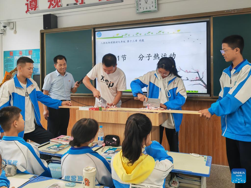 Hu Yongxiang (kedua dari kiri di podium) melihat murid-muridnya memotong bawang semasa kelas fizik di Sekolah Menengah Ketiga Daerah Hongsibu, bandar Wuzhong, Wilayah Autonomi Hui Ningxia, barat daya China, 4 September 2024. (Xinhua/Ai Fumei)