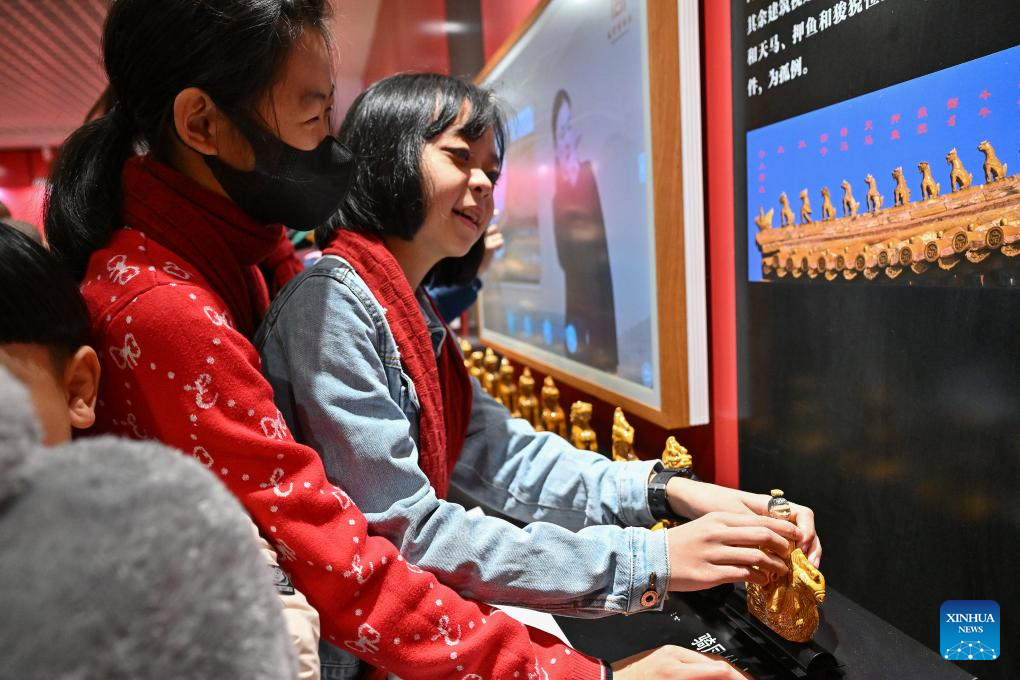 Pelajar dari Sekolah Orang Buta Beijing menyentuh model haiwan hiasan atap di Galeri Pengalaman Sensori Muzium Istana, Beijing, 1 Disember 2024. (Xinhua/Lin Xin)